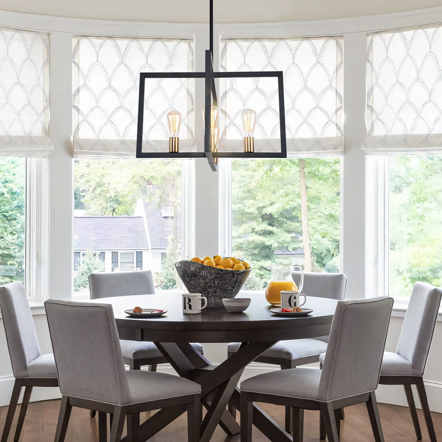 A rectangular bronze hanging light with clear glass globes hangs from a vintage living room ceiling. The light casts a warm, inviting glow on the space.