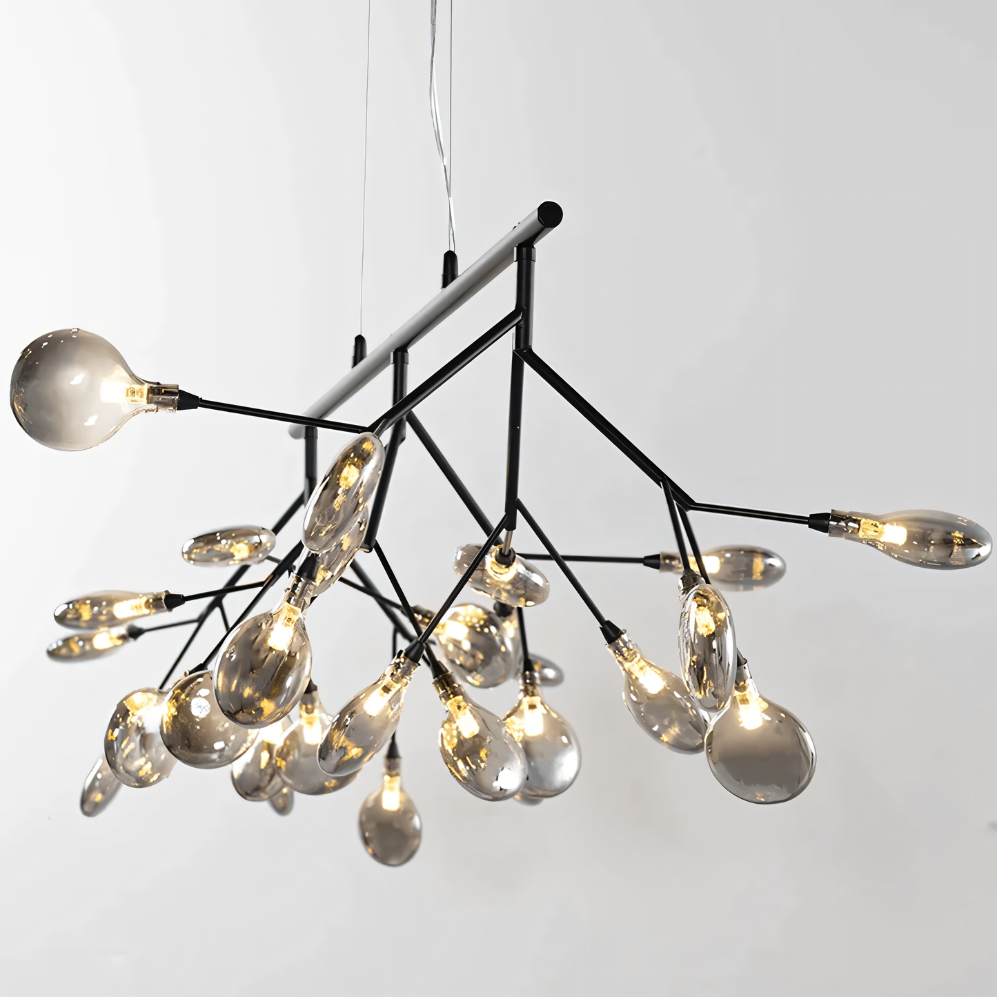 A black, circular chandelier with rods tipped with LED bulbs hangs from a dining room ceiling. The chandelier casts a warm, inviting glow on the space.