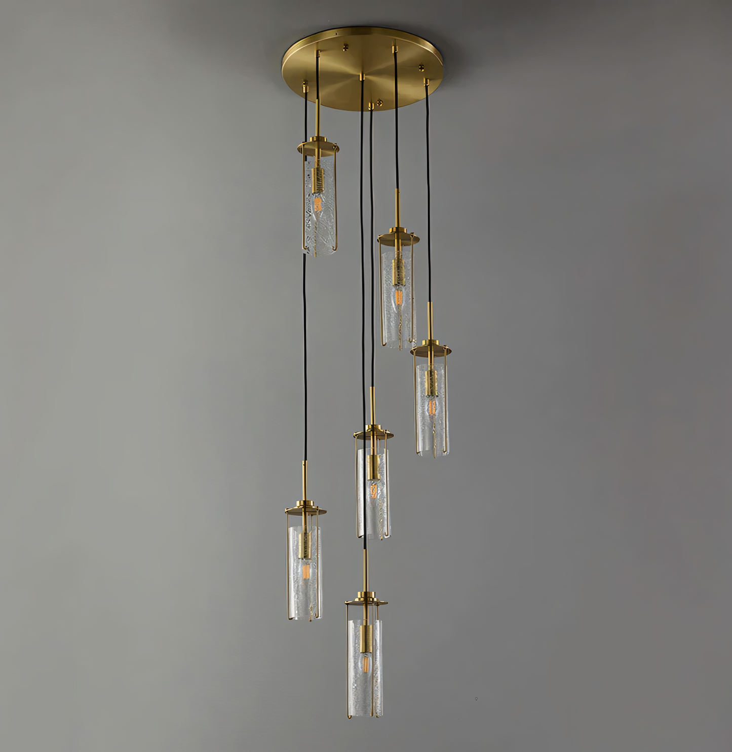A 6-light brass chandelier with crackle glass globes hangs from the double-height ceiling of a beach villa staircase. The chandelier casts a warm, inviting glow on the space.