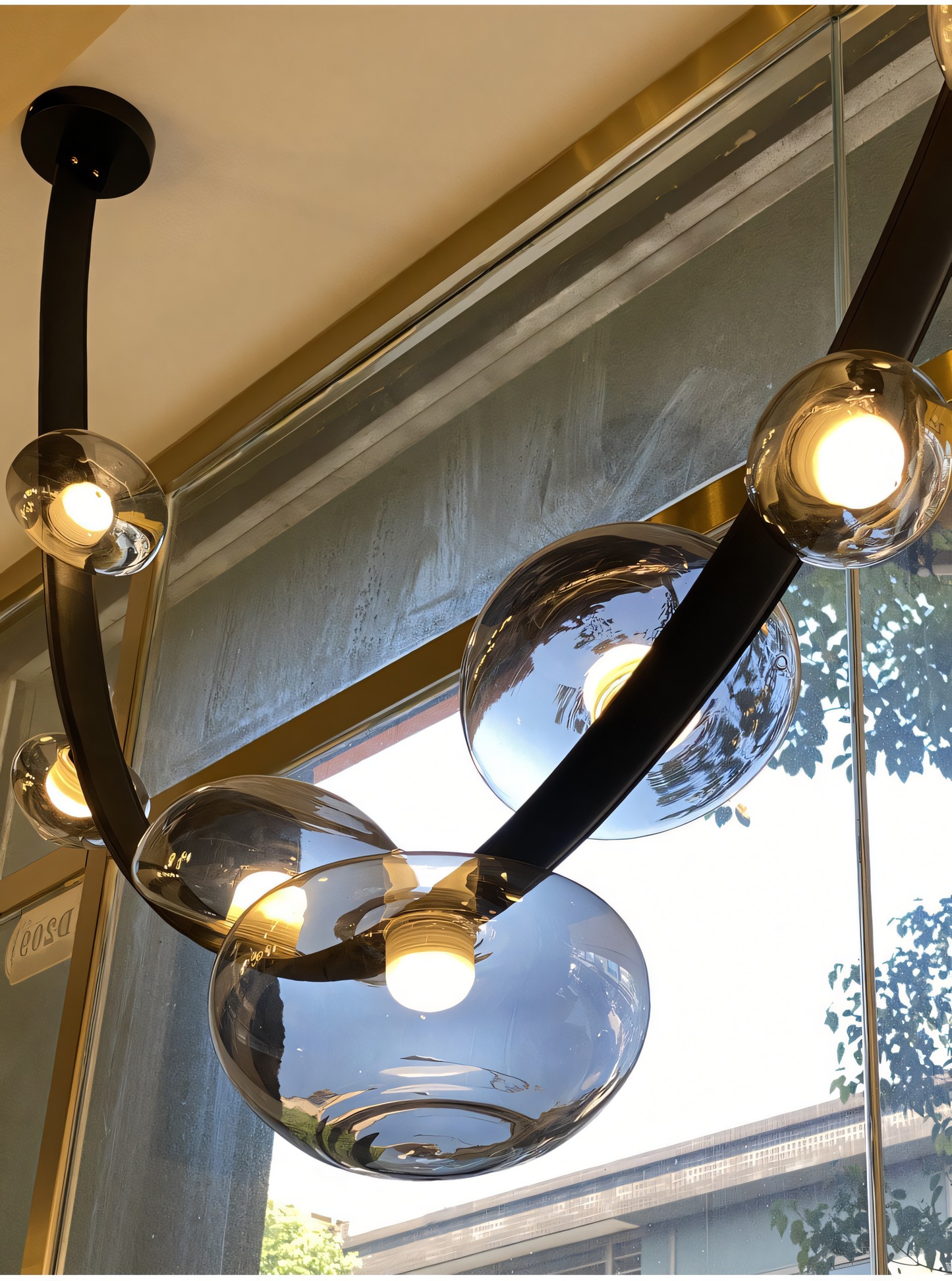 A modern chandelier with a black metal frame, black leather belt, and smoky glass globes hangs from a dining room ceiling. The chandelier casts a warm, inviting glow on the space.