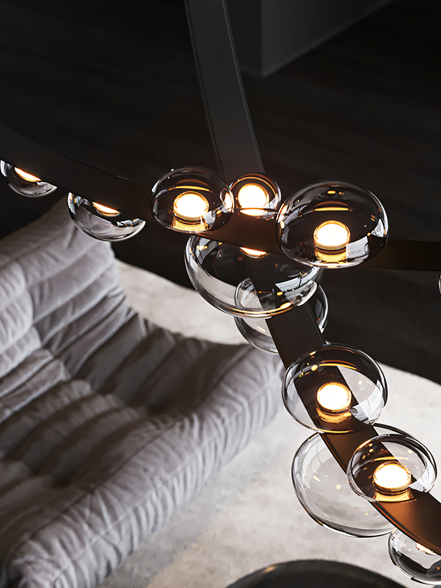 This dining room chandelier boasts a unique design with a black metal frame, black leather belt, and smoky glass globes, adding a touch of modern sophistication.