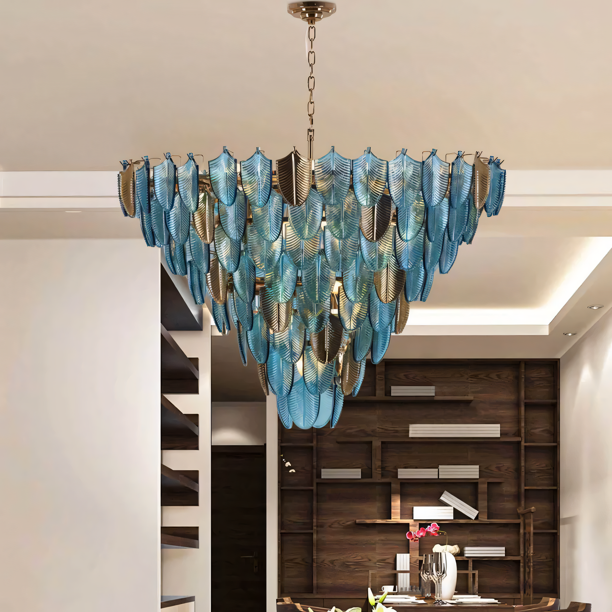The Gratus Luxe Modern Glass Leaf Chandelier, a nature-inspired centerpiece, hangs above a dining table in a modern beach villa. The chandelier's soft light fills the room.
