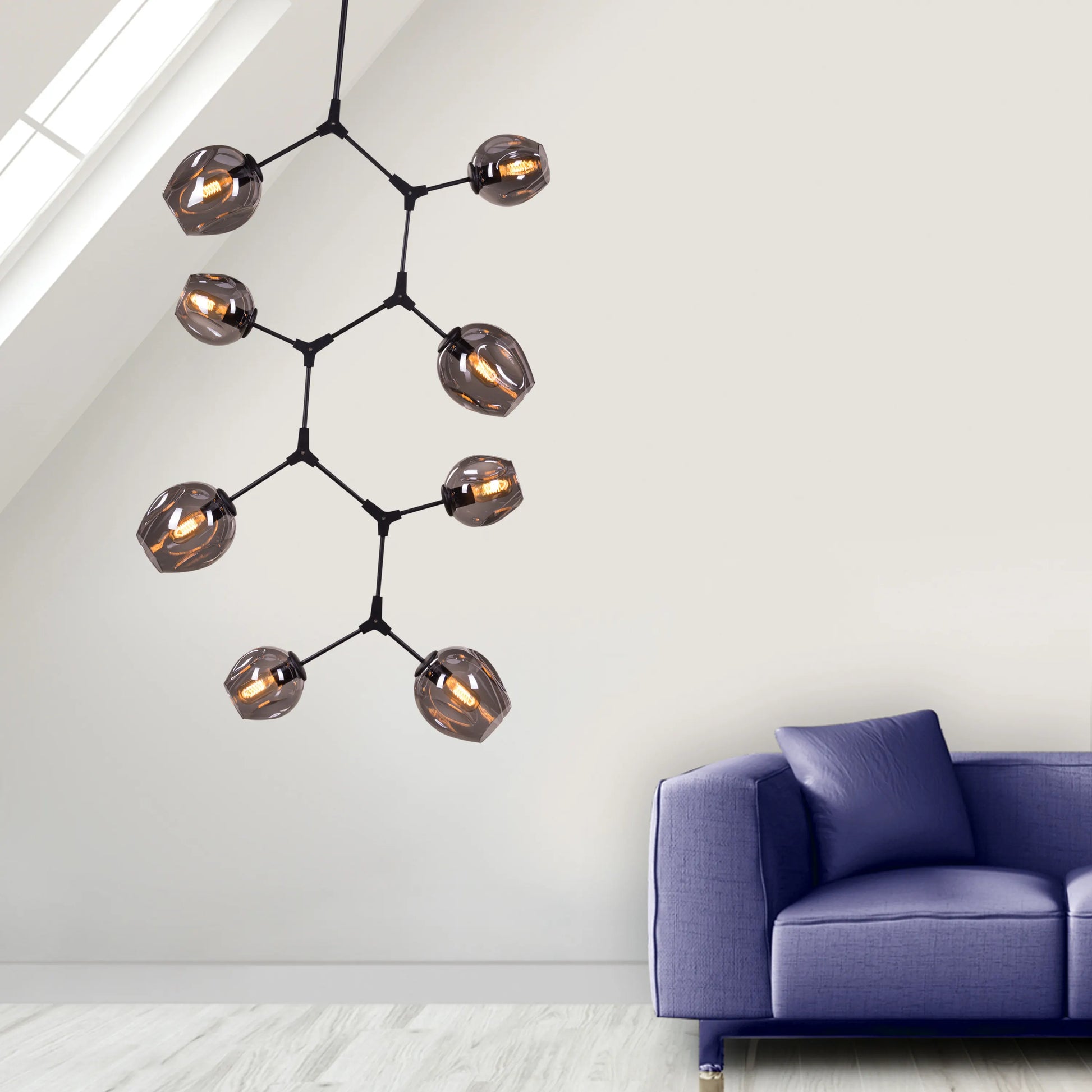 Twist In The Tale 8-head glass chandelier in black and smokey grey, illuminating a modern living room.