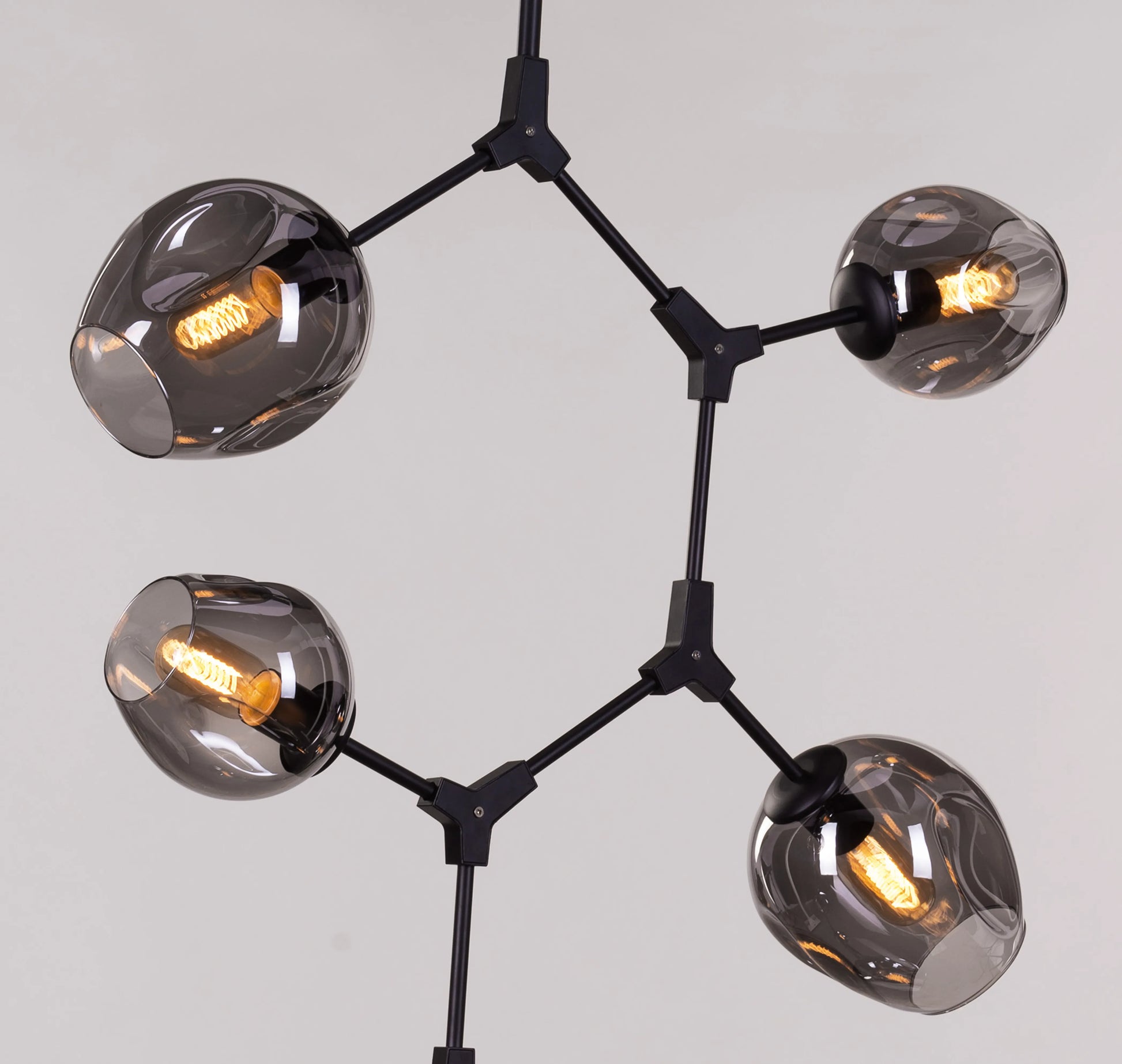 Twist In The Tale 8-head glass chandelier in black and smokey grey, illuminating a modern living room.