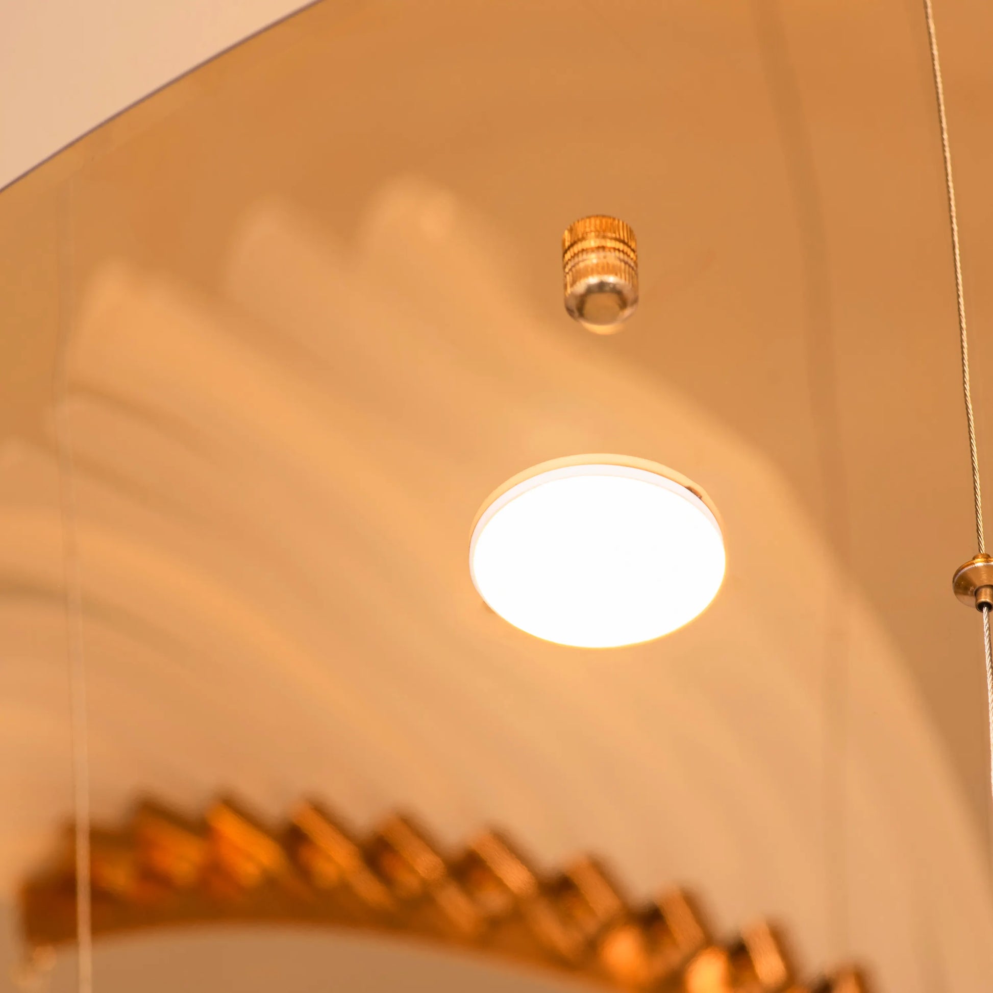 Large gold and white Chefs Kiss chandelier with frosted glass, hanging in a spacious living room