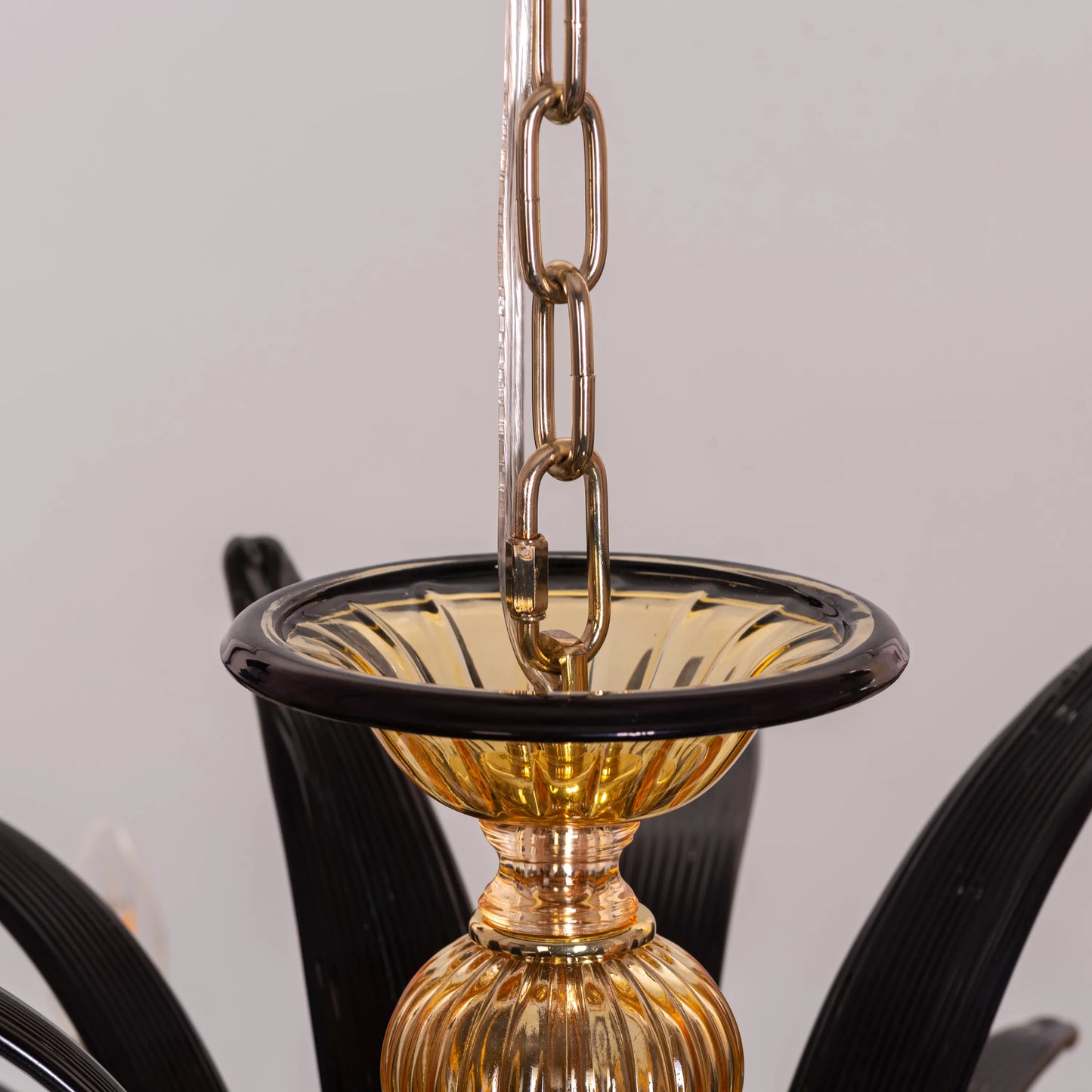 Large "Melodrama" chandelier with amber textured glass and black metal frame, dramatically illuminated in a spacious room.