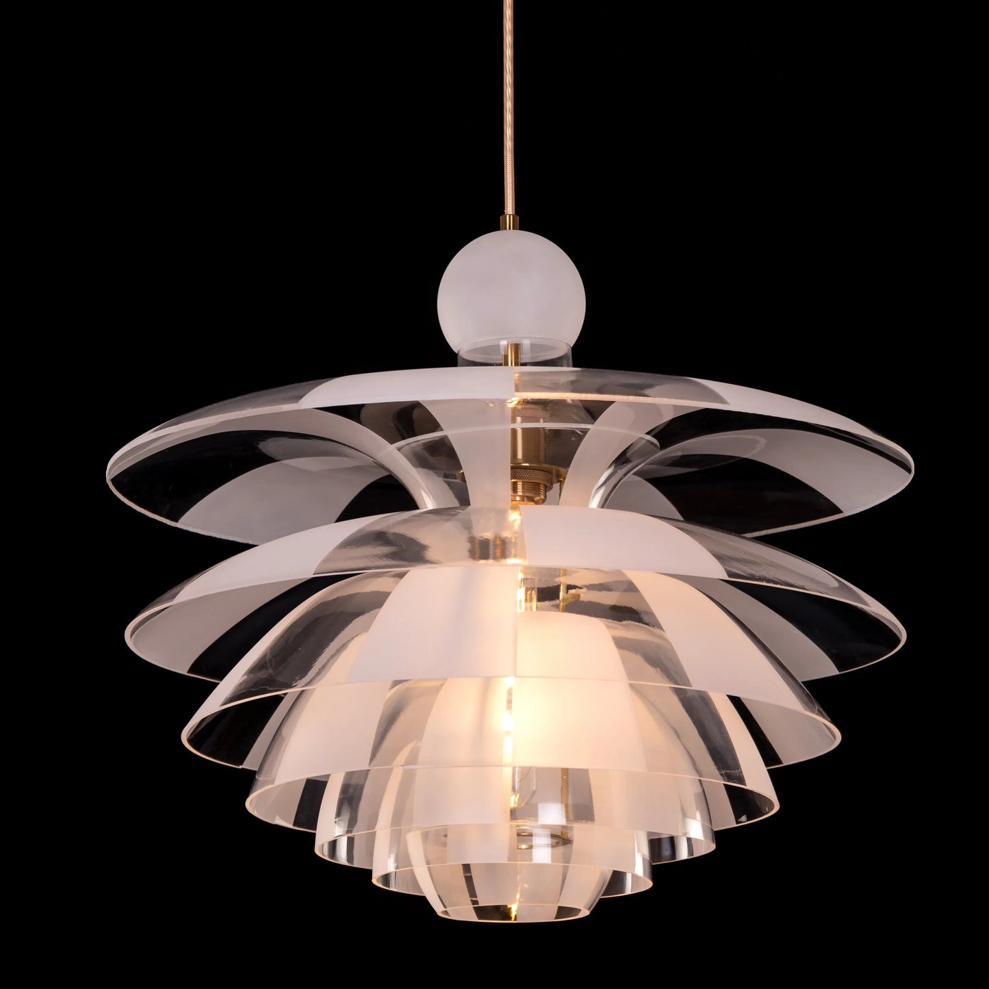 A striking pendant light named 'Find Your Truth,' featuring a unique geometric design that combines metal and glass elements. The fixture has a polished finish that reflects light beautifully, creating a captivating visual effect. Its modern aesthetic and artistic shape serve as a statement piece, adding elegance and intrigue to any room.