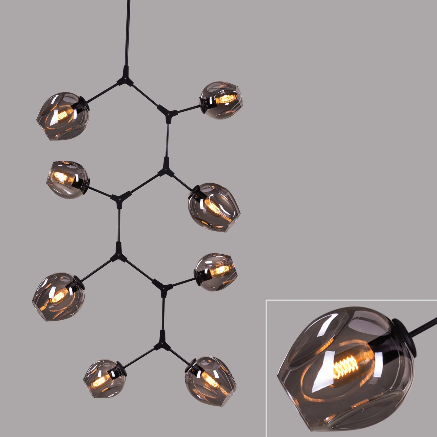 Twist In The Tale 8-head glass chandelier in black and smokey grey, illuminating a modern living room.