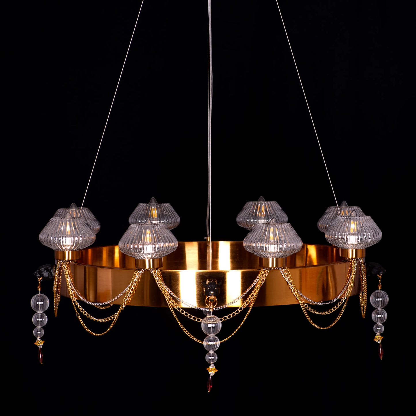 Large "Heart Is Beating" gold and clear glass chandelier, illuminated and suspended in a spacious, elegant room.
