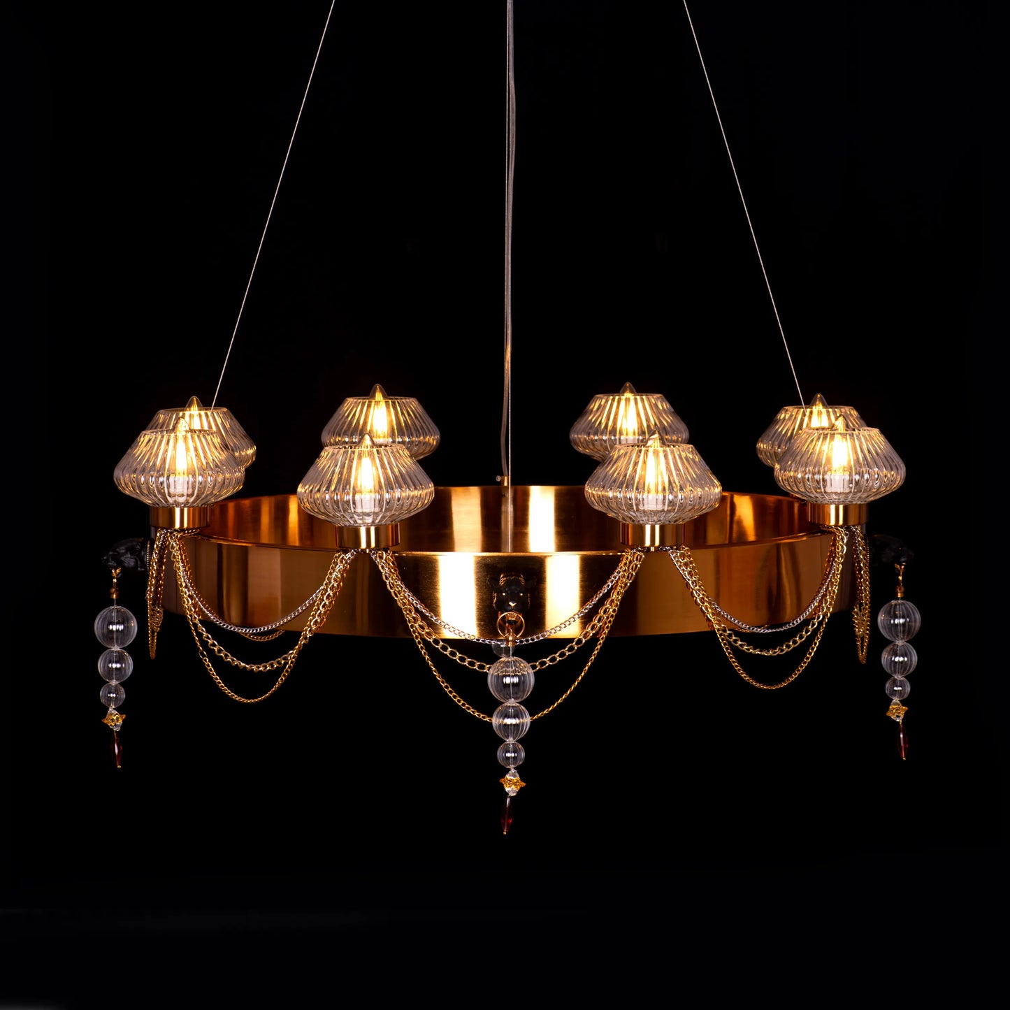 Large "Heart Is Beating" gold and clear glass chandelier, illuminated and suspended in a spacious, elegant room.