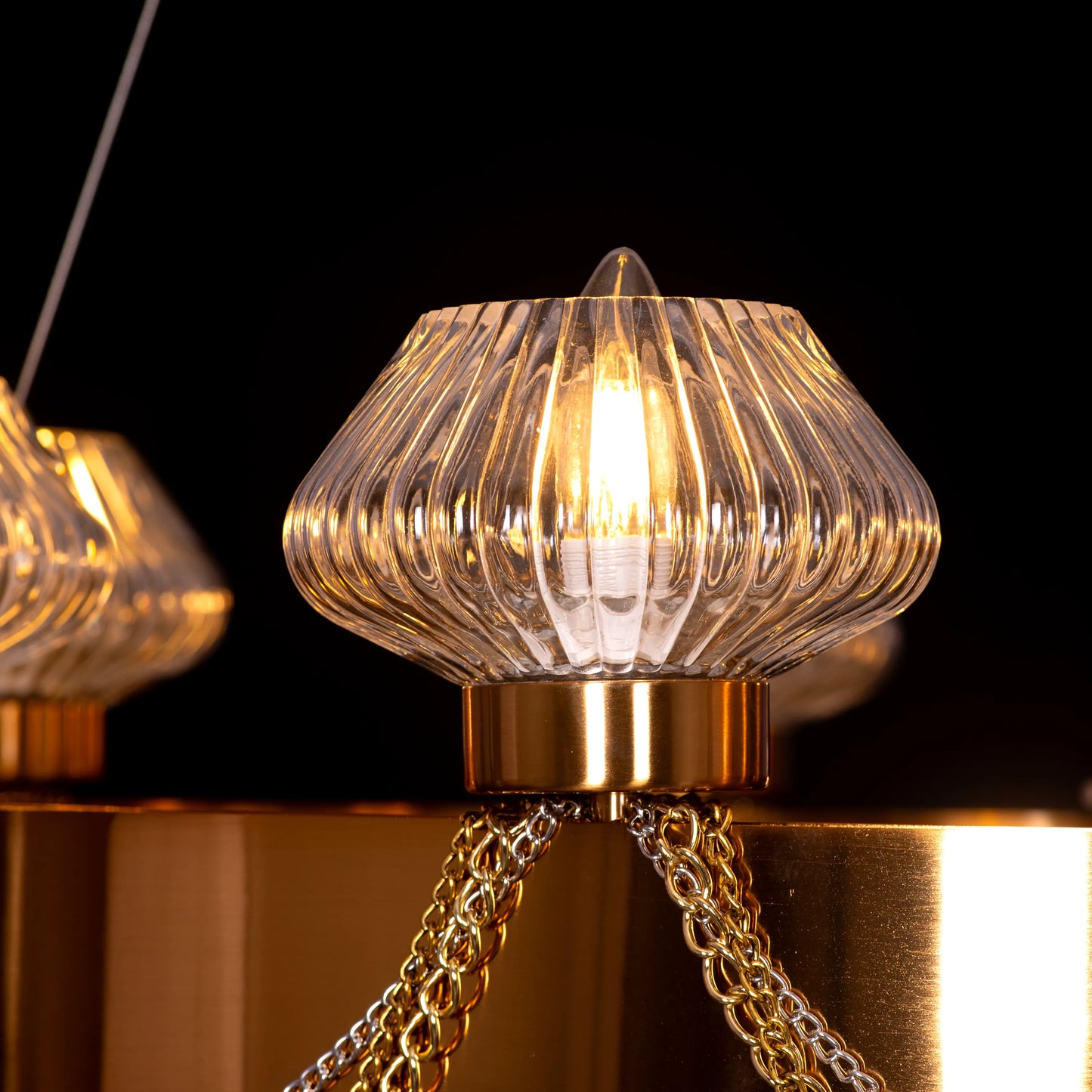 Large "Heart Is Beating" gold and clear glass chandelier, illuminated and suspended in a spacious, elegant room.