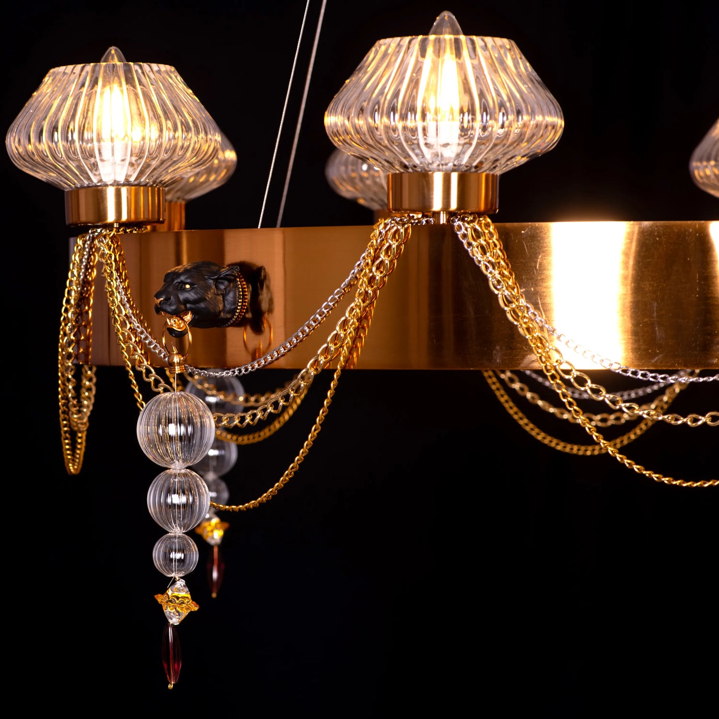 Large "Heart Is Beating" gold and clear glass chandelier, illuminated and suspended in a spacious, elegant room.
