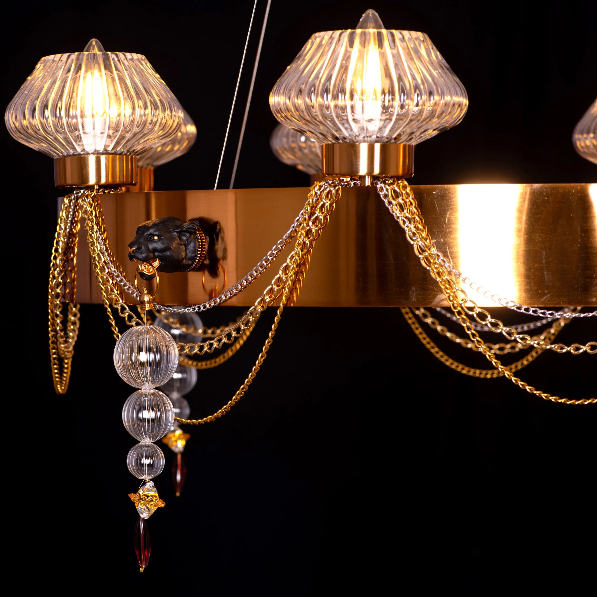 Large "Heart Is Beating" gold and clear glass chandelier, illuminated and suspended in a spacious, elegant room.