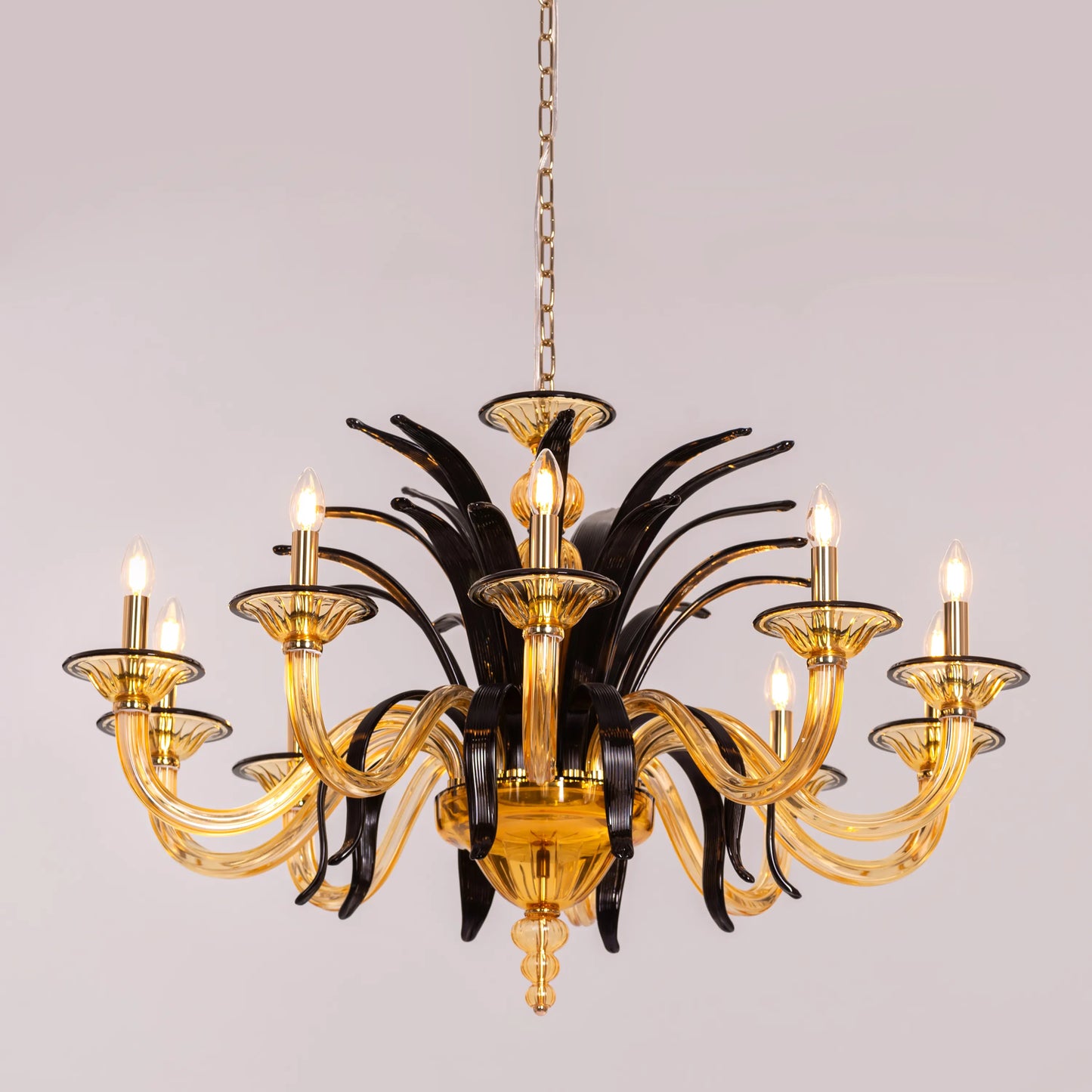 Large "Melodrama" chandelier with amber textured glass and black metal frame, dramatically illuminated in a spacious room.