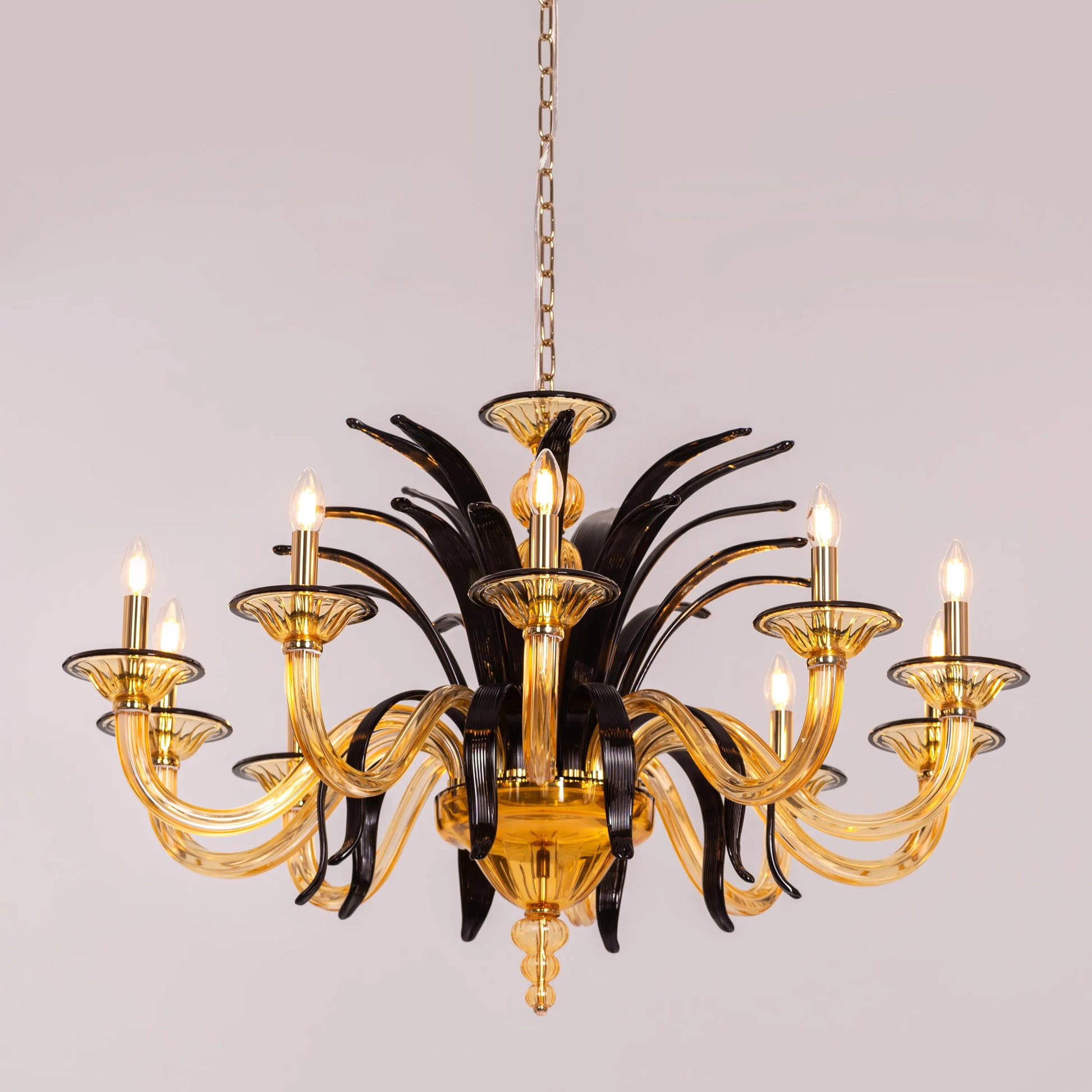 Large "Melodrama" chandelier with amber textured glass and black metal frame, dramatically illuminated in a spacious room.