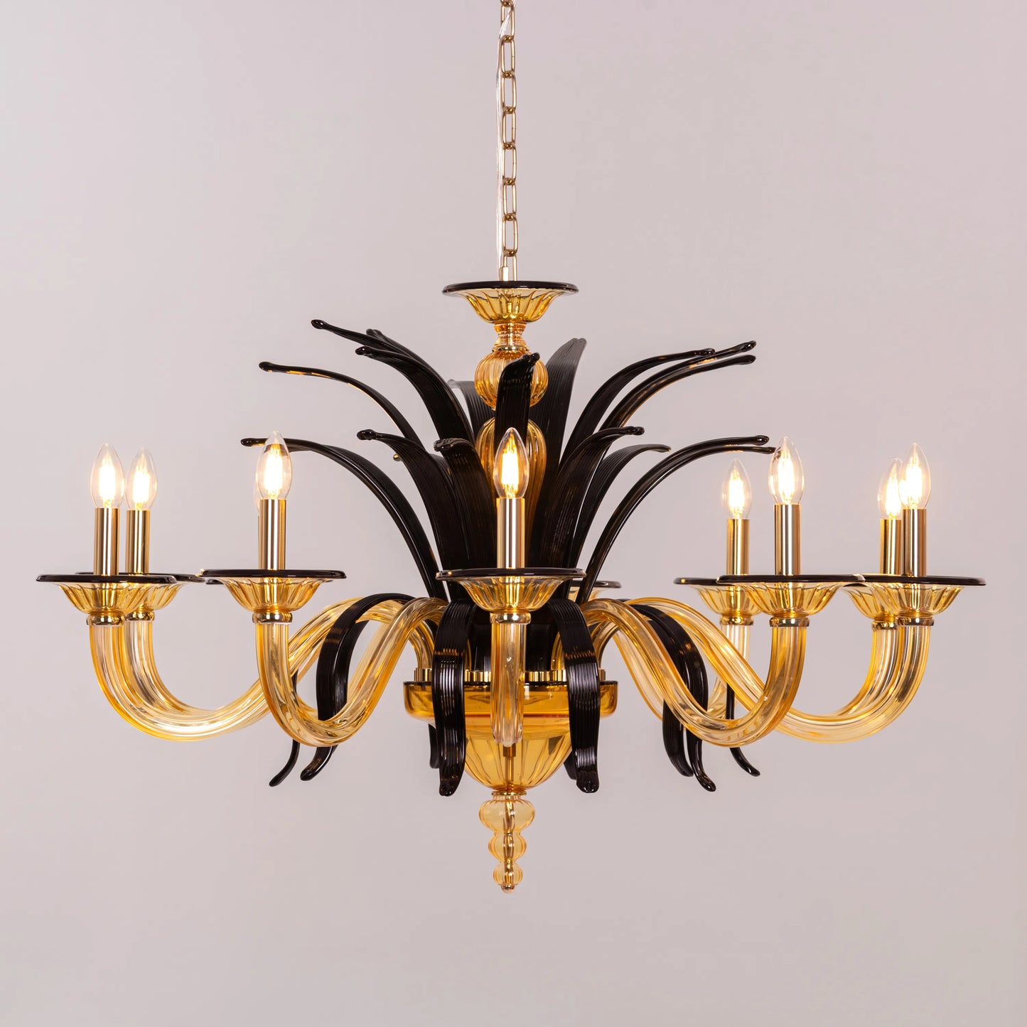 Large "Melodrama" chandelier with amber textured glass and black metal frame, dramatically illuminated in a spacious room.