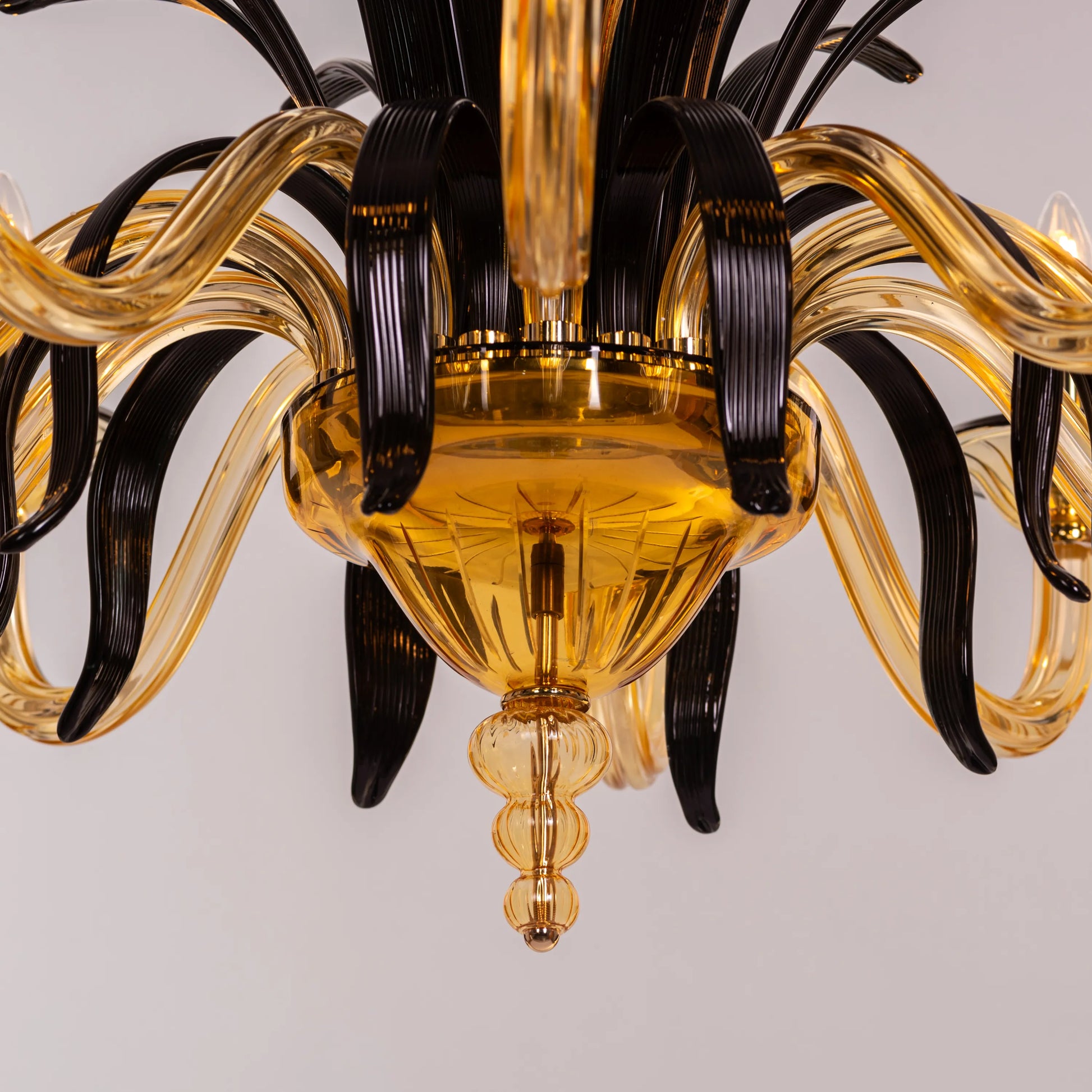 Large "Melodrama" chandelier with amber textured glass and black metal frame, dramatically illuminated in a spacious room.
