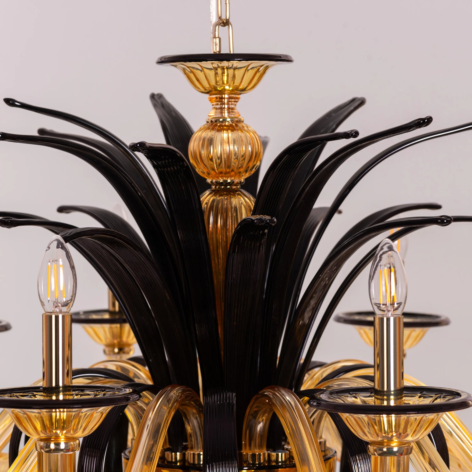 Large "Melodrama" chandelier with amber textured glass and black metal frame, dramatically illuminated in a spacious room.
