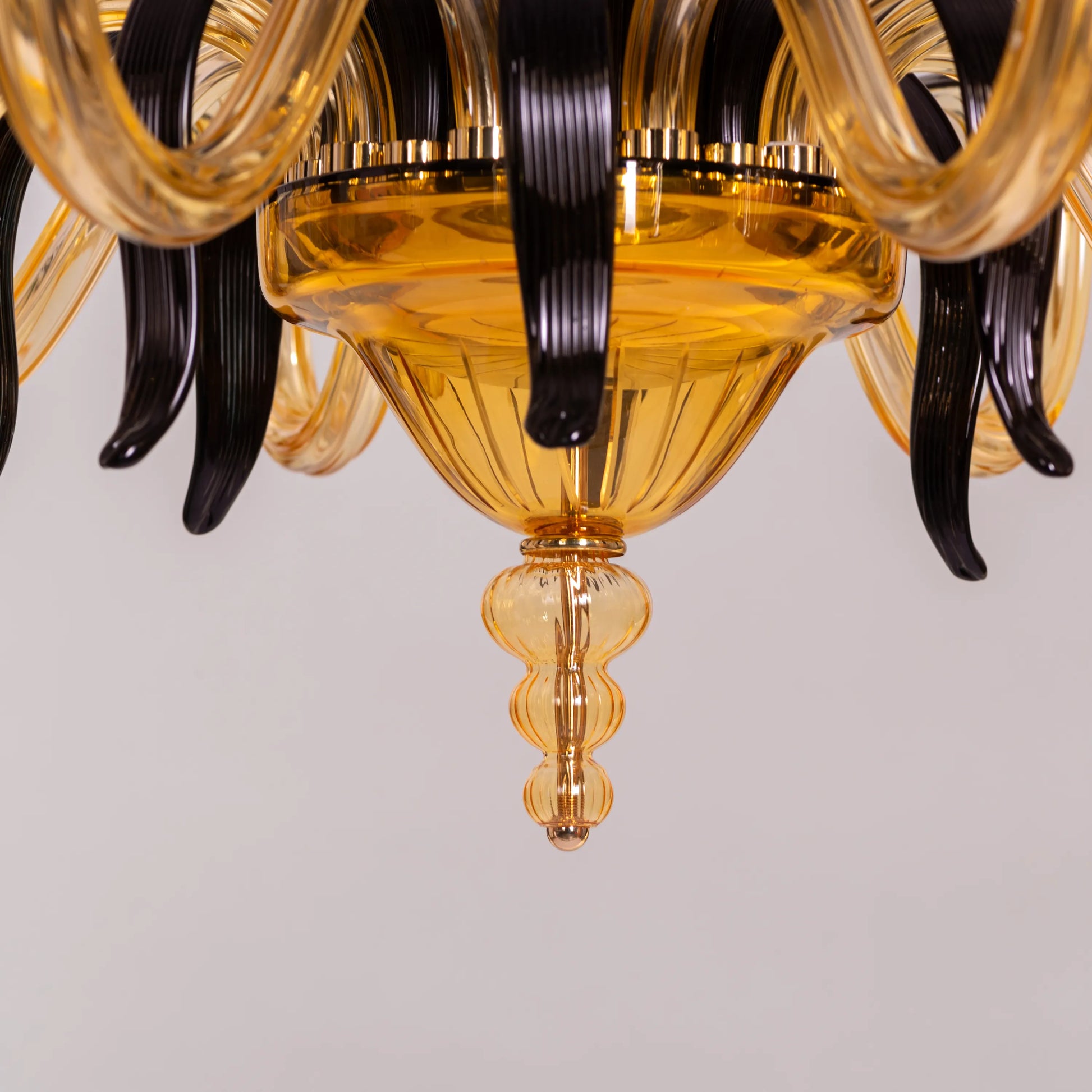 Large "Melodrama" chandelier with amber textured glass and black metal frame, dramatically illuminated in a spacious room.