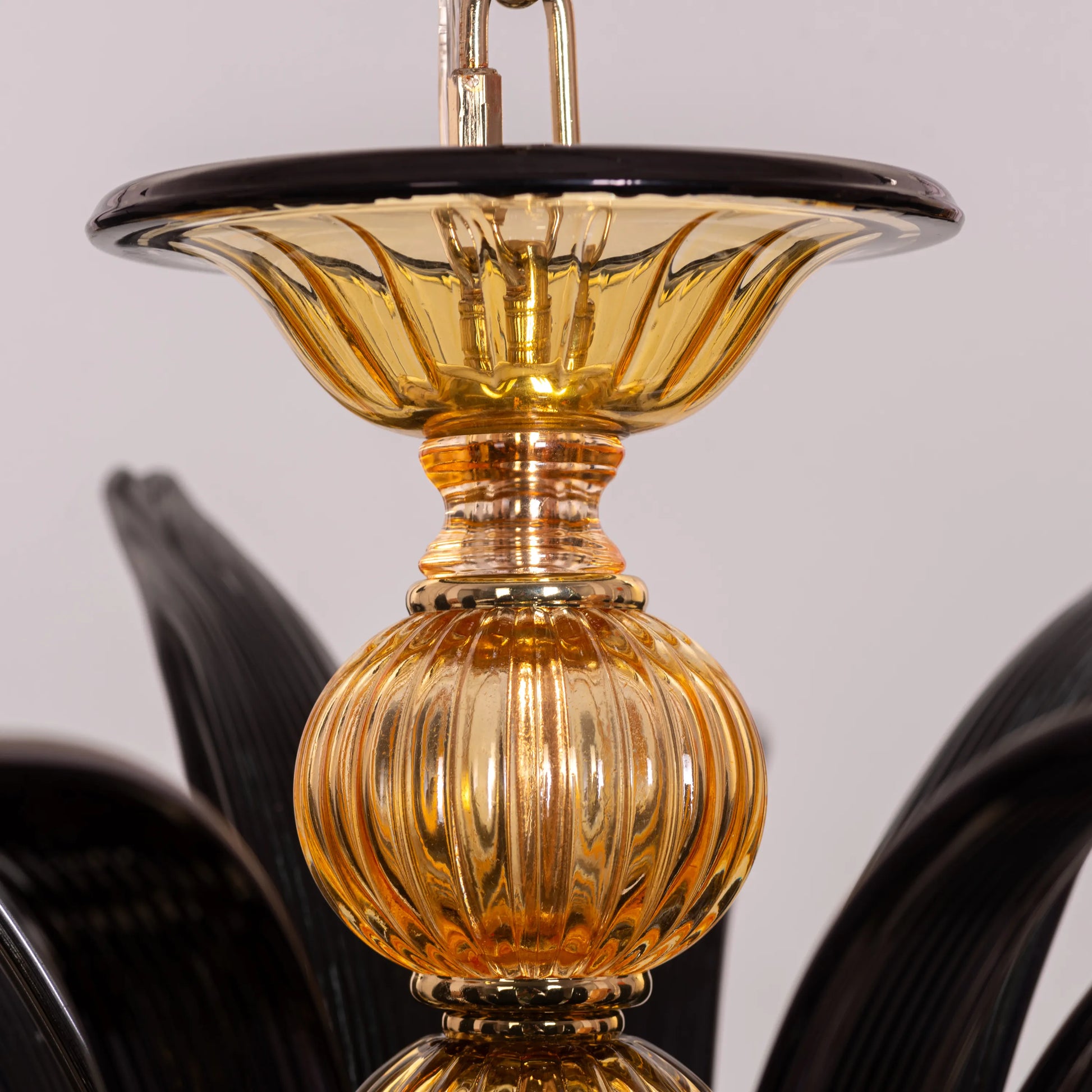 Large "Melodrama" chandelier with amber textured glass and black metal frame, dramatically illuminated in a spacious room.