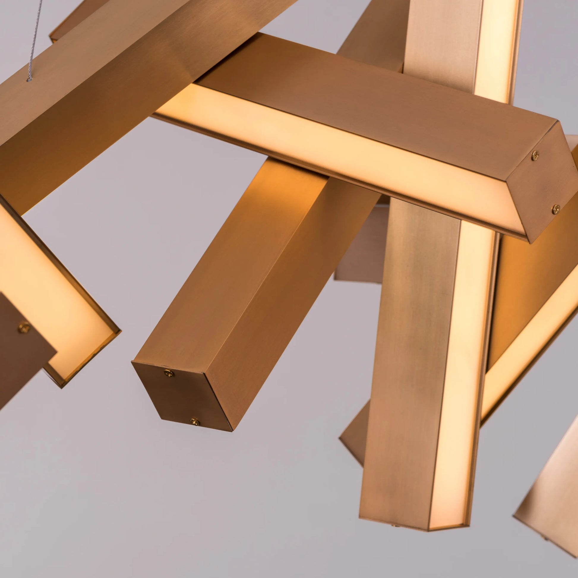 Large "Glow Miles" gold chandelier with multiple LED light sources, dramatically illuminated in a spacious, modern room.