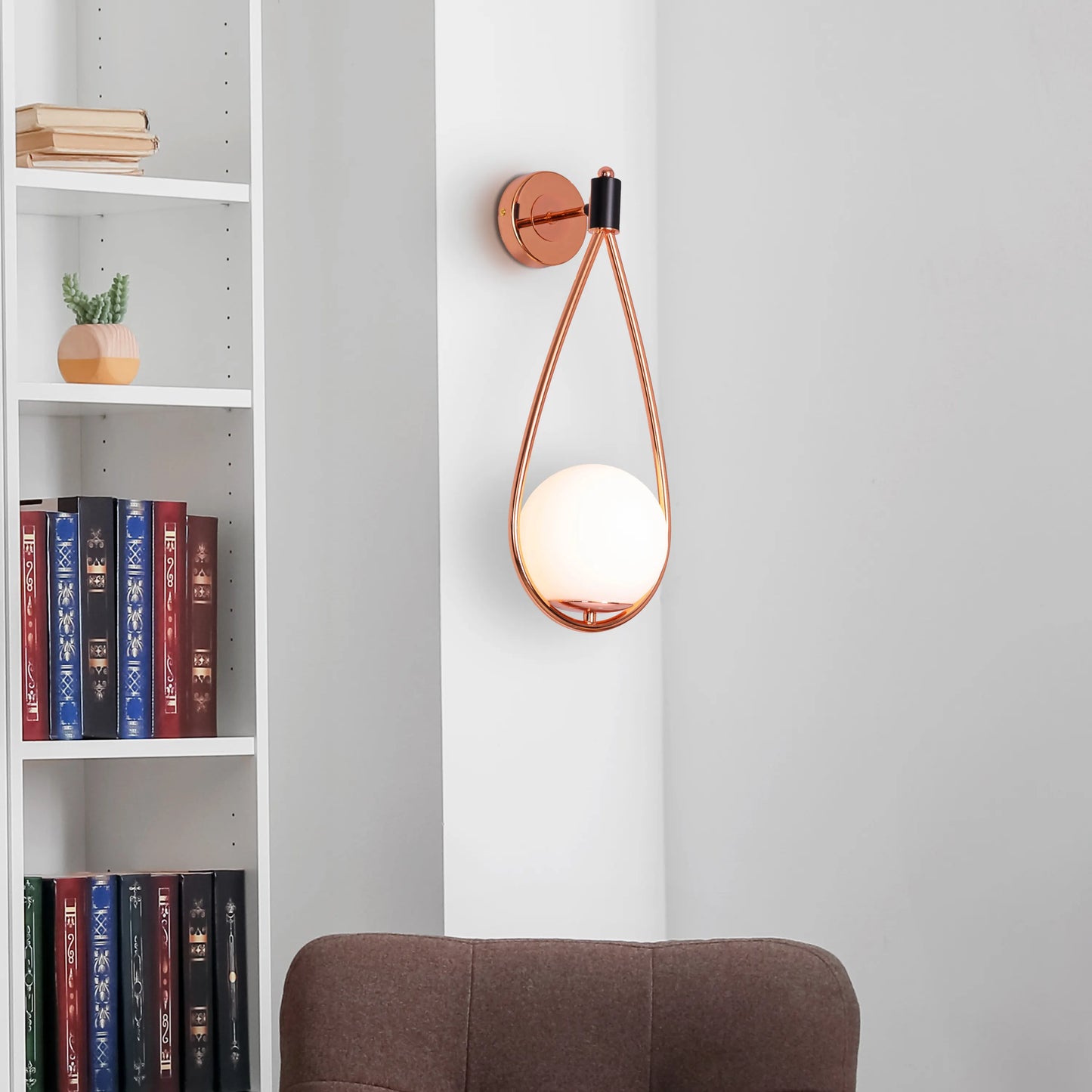 Sleek glass and metal wall light adding warmth to a minimalist living room.